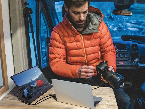 Mann mit Kamera, Laptop und VR16-OLED in einem Van
