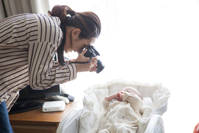 Fotografin beim Babyshooting. Das Neugeborene liegt in einer Wiege.
