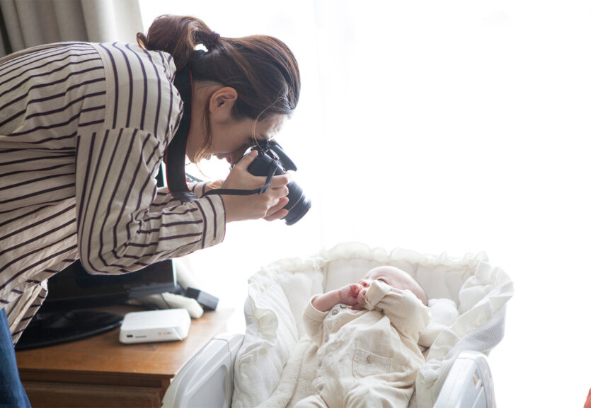 Fotografin beim Babyshooting. Das Neugeborene liegt in einer Wiege.