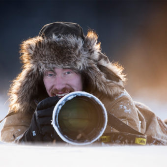 Der Fotograf Florian Smit liegt mit seiner Nikon-Kamera im Schnee