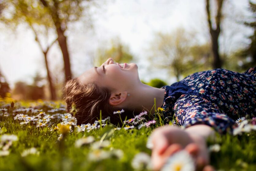 Frau liegt auf Blumenwiese