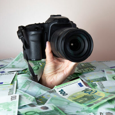 Kamera in der Hand mit Geldscheinen